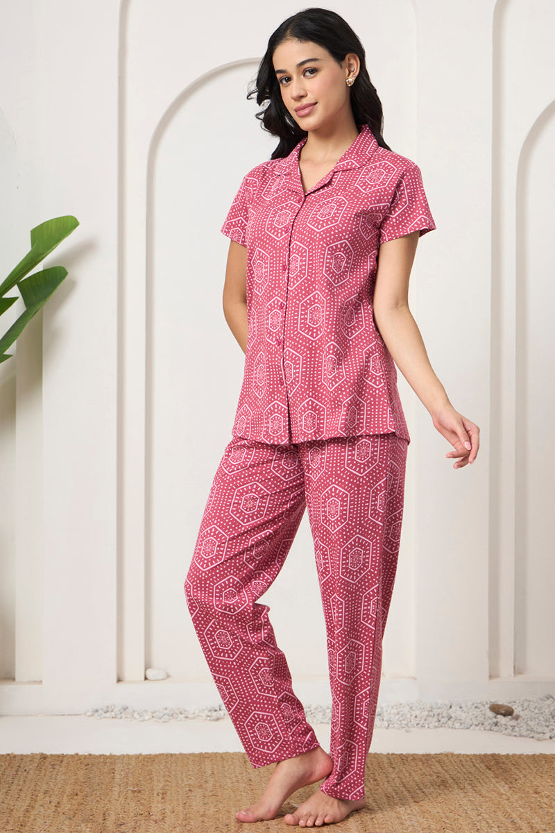 Woman standing in a pink bandhani print shirt and pants set, hand in pocket