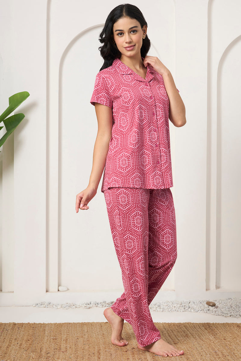 Woman posing in a pink bandhani print shirt and pants, hand in hair
