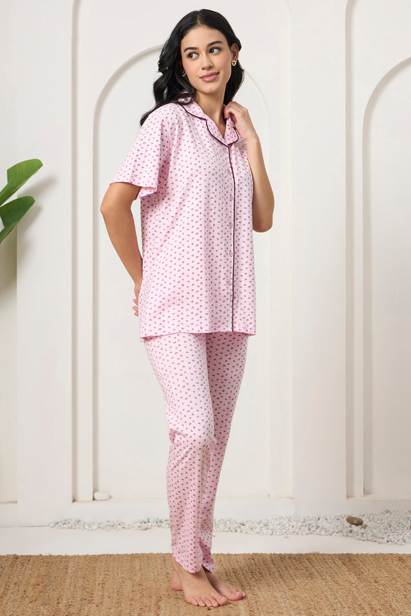 Woman standing in a pink printed shirt and pants set, looking to the side