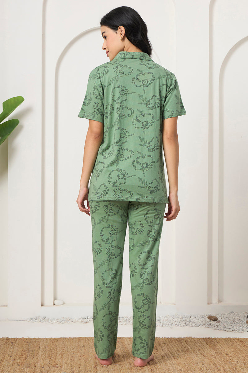 Back view of a woman wearing a sage green floral print shirt and pants