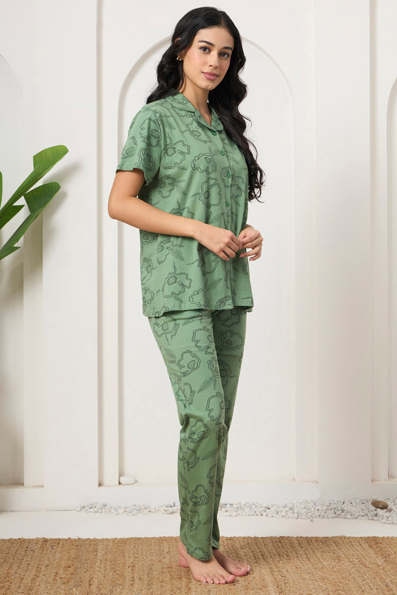 Woman posing in a sage green floral print shirt and pants set, side view