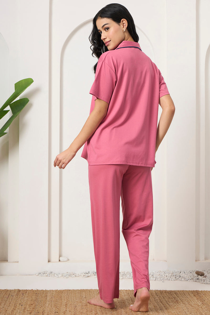 Back view of a woman wearing a pink collared shirt and pants set