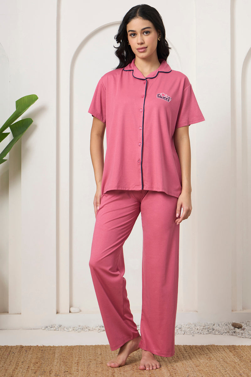 Woman standing in a pink collared shirt and pants set