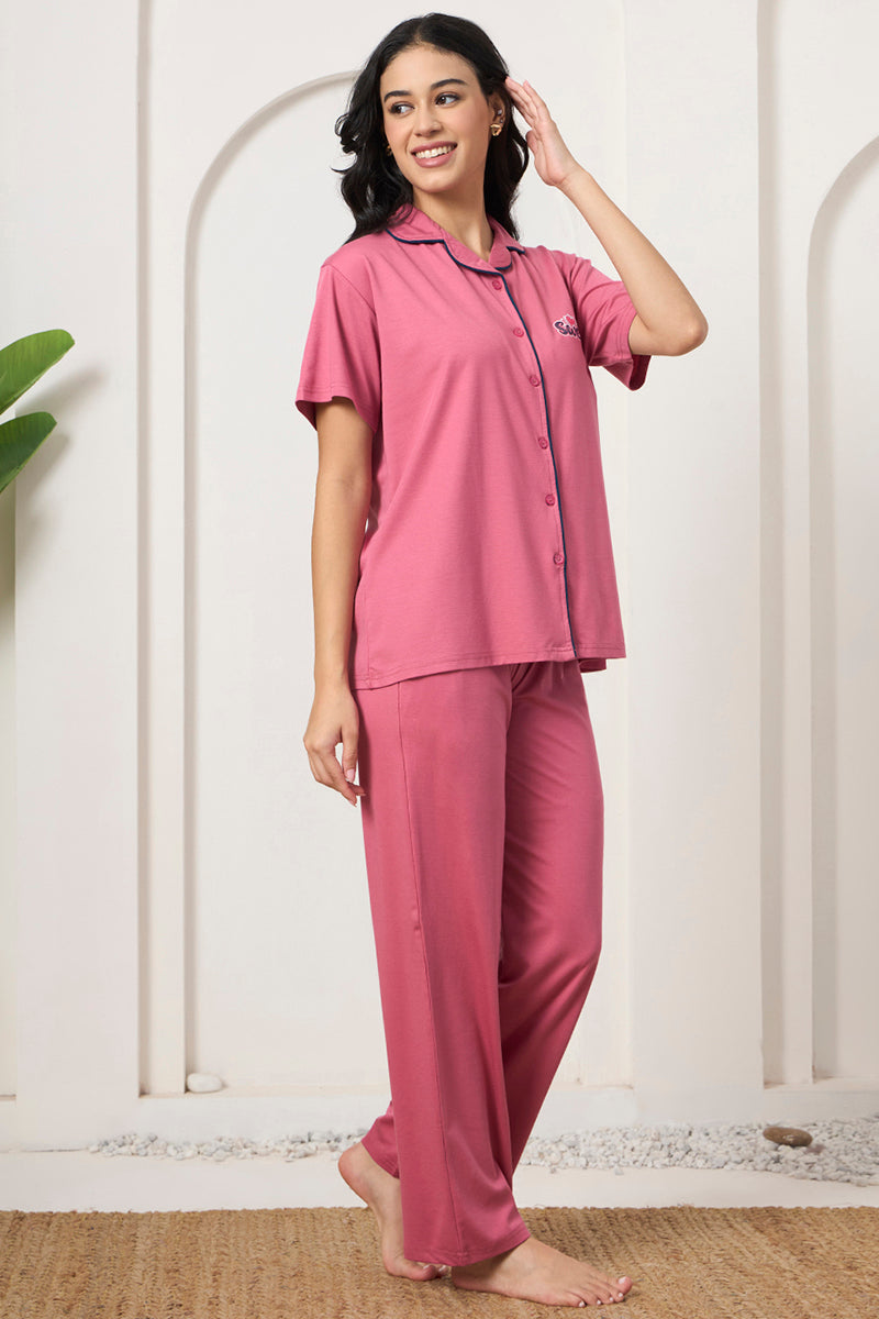 Woman looking sideways in a pink button down shirt and pants set