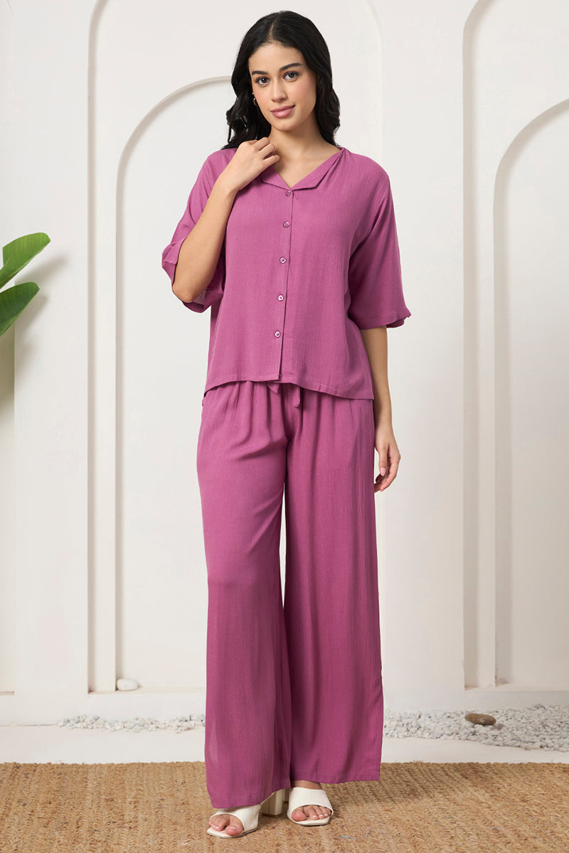 Woman standing in a mauve button down shirt and wide leg pants