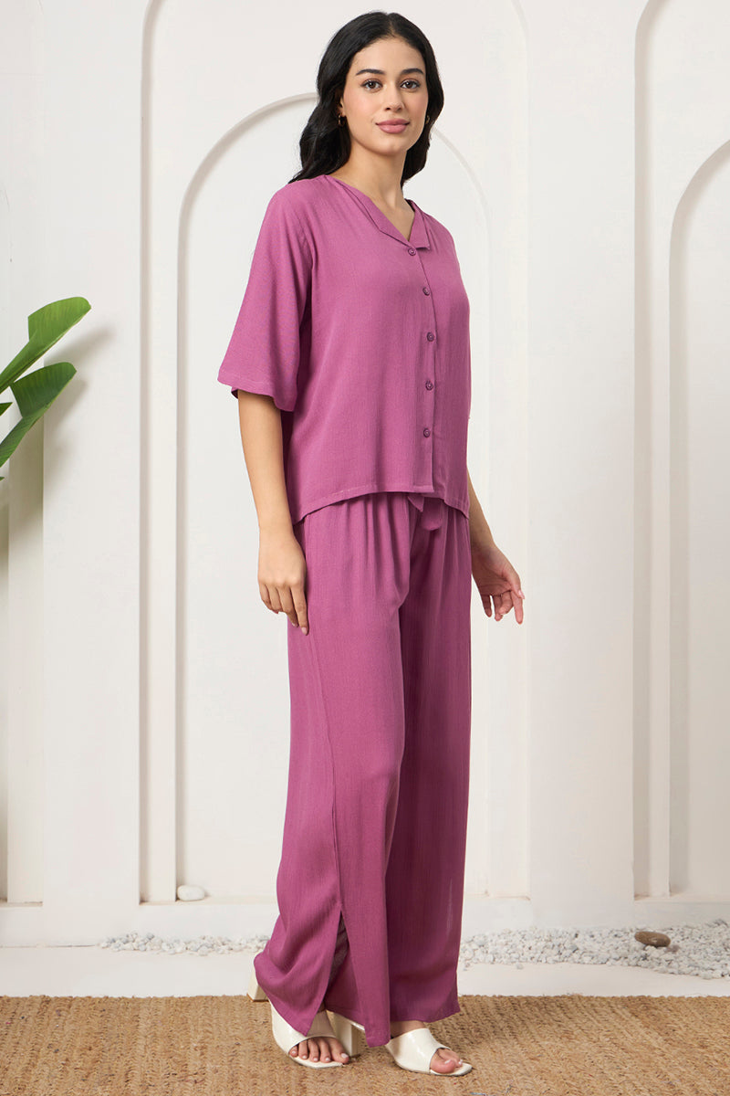 Woman posing in a mauve button down shirt and wide leg pants