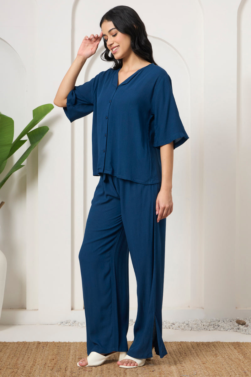 Woman posing in a teal button down shirt and pants, side view