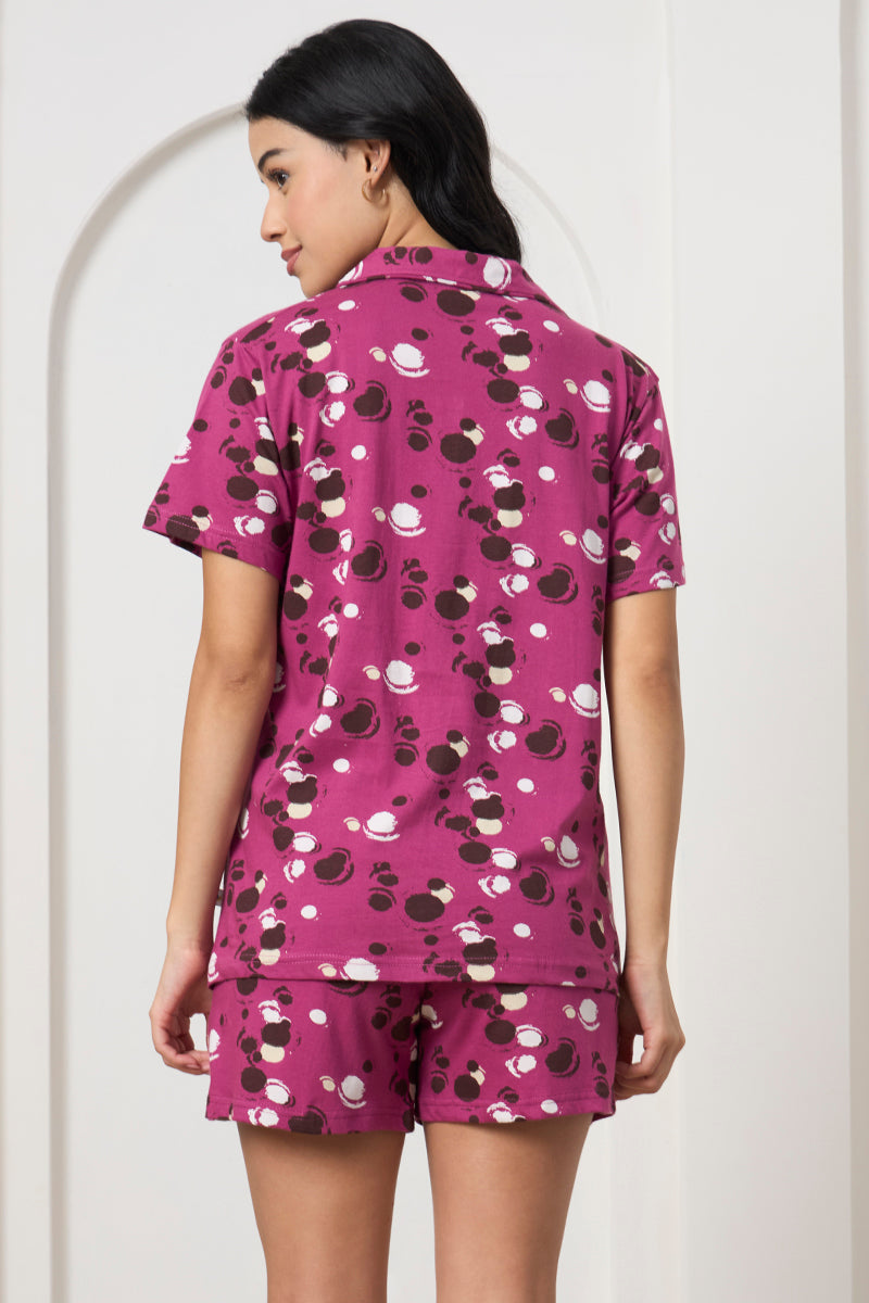 Back view of a woman wearing a magenta polka dot shirt and shorts