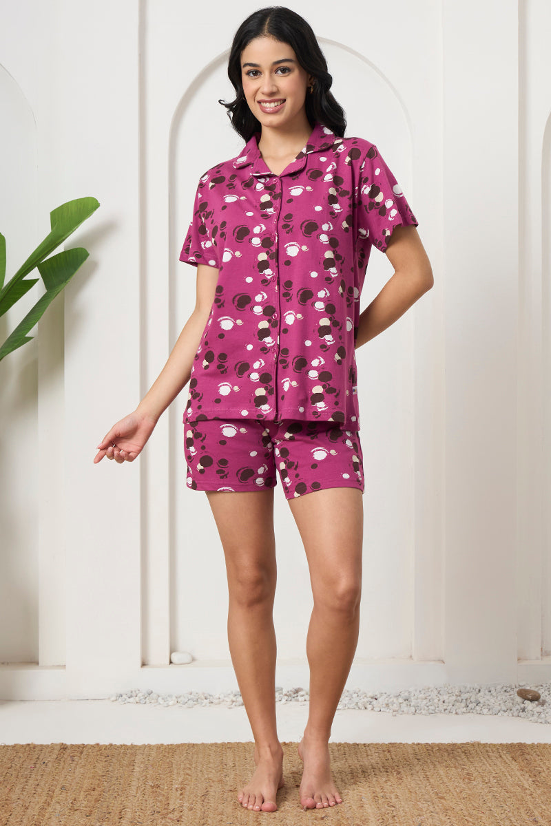 Woman smiling in a magenta polka dot shirt and shorts set, front view