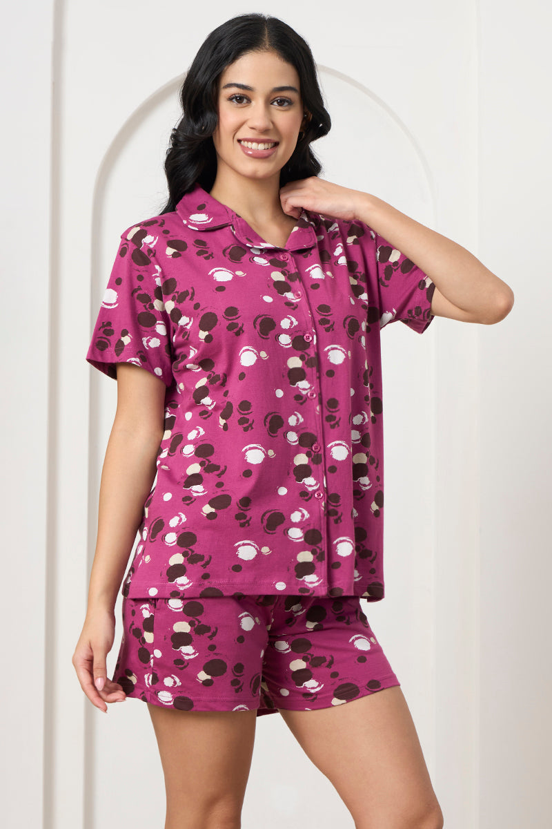 Woman smiling in a magenta polka dot shirt and matching shorts