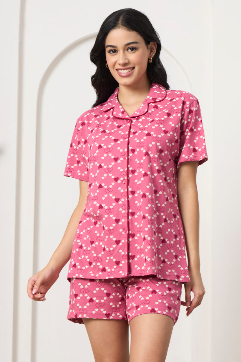 Woman smiling in a pink heart print shirt and matching shorts, front view