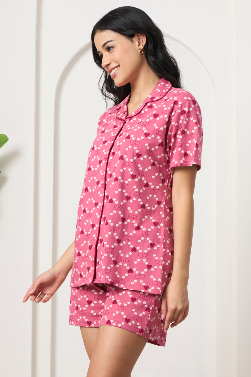 Woman posing in a pink heart print shirt and shorts set, side view