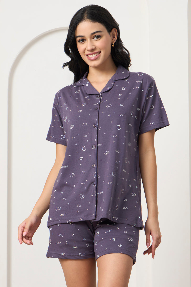 Woman standing in a grey printed shirt and matching shorts, front view
