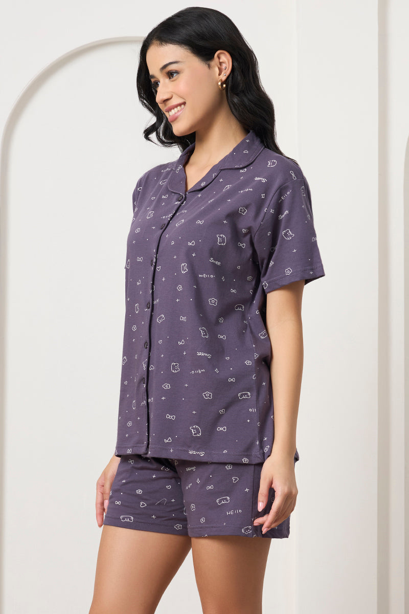 Woman smiling in a grey printed shirt and shorts set, side view