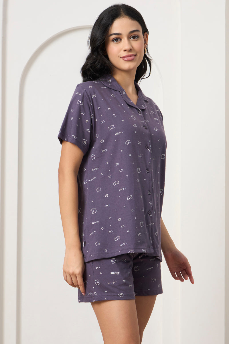 Woman posing in a grey printed shirt and shorts set, side view