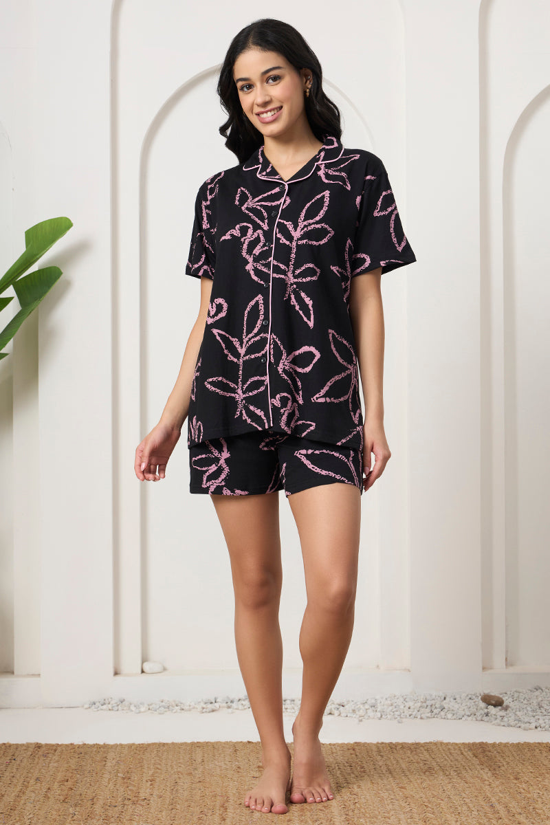 Woman standing in a black and pink leaf print shirt and shorts set