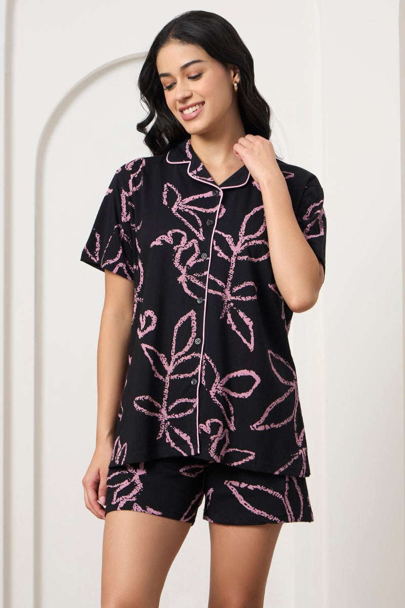 Woman smiling in a black and pink leaf print shirt and matching shorts