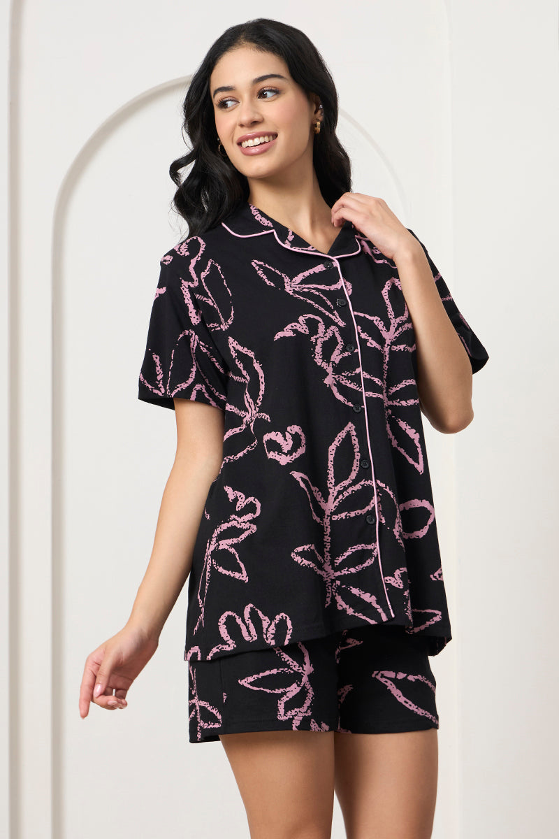 Woman posing in a black and pink leaf print co-ord set, looking to the side