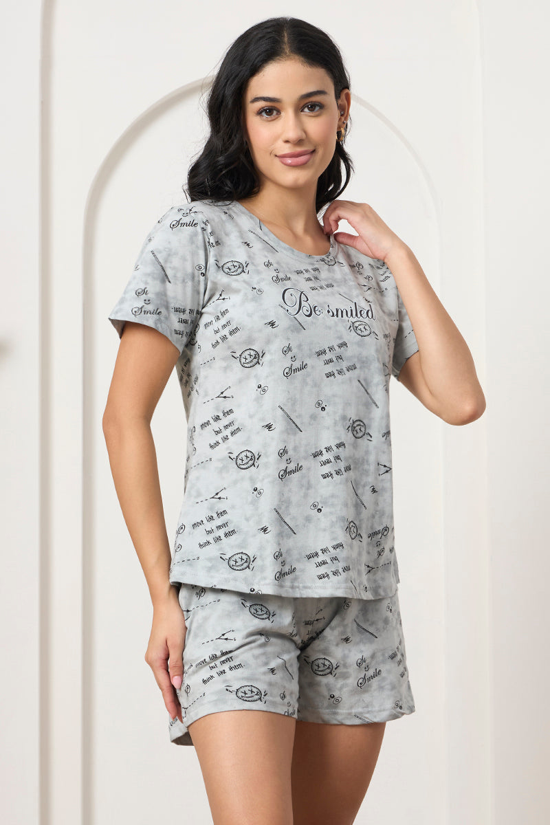 Woman smiling with hand near shoulder wearing a grey printed set