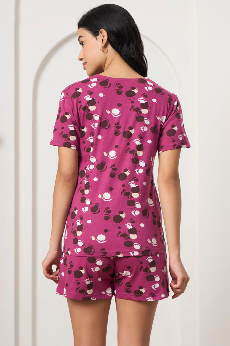 Back view of a woman wearing a magenta polka dot print t-shirt and shorts set