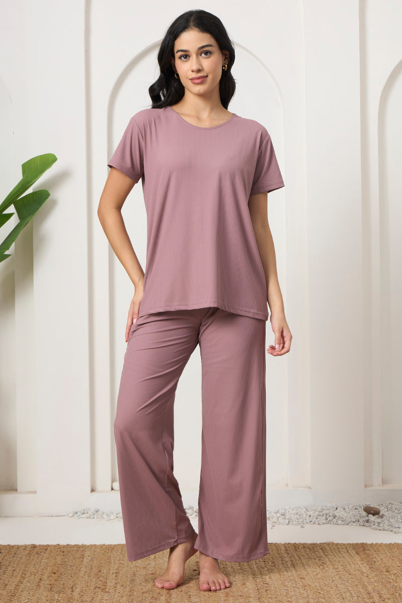 Woman standing in a mauve ribbed loungewear set on a jute rug