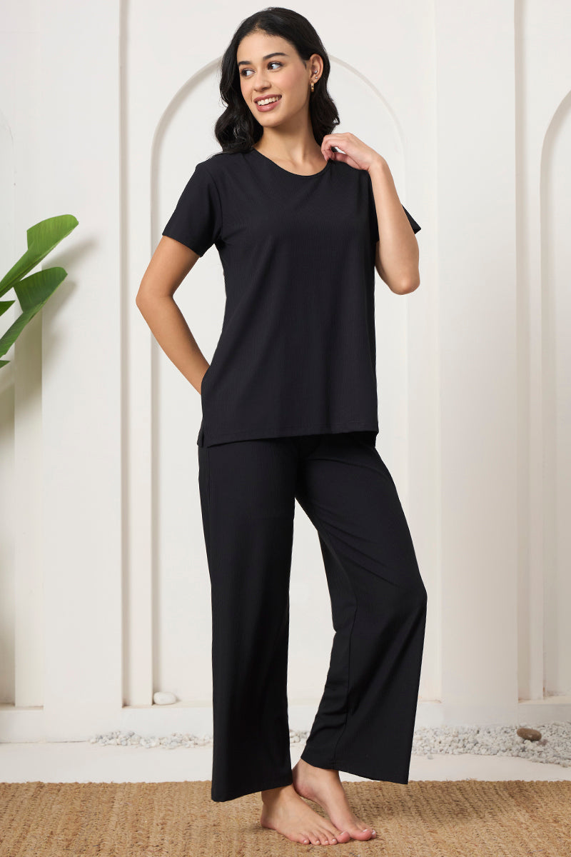Woman in a black ribbed loungewear set against an arched wall