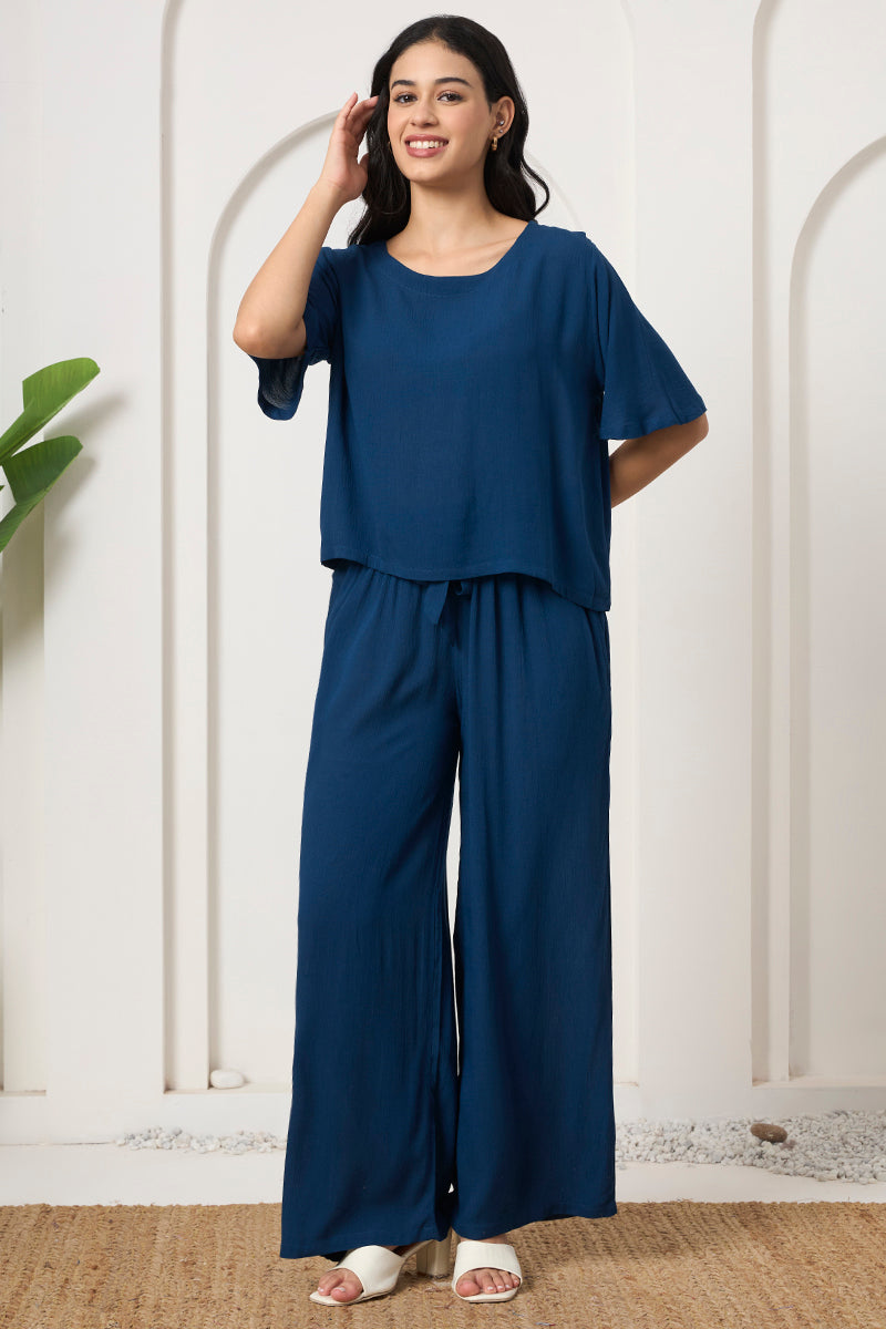 Woman smiling in a teal crop top and wide leg tie waist pants