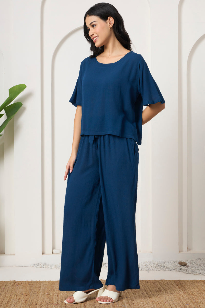 Woman posing in a teal crop top with wide leg pants, side view