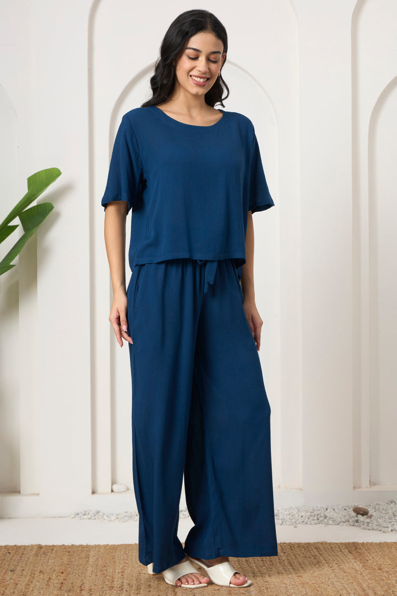 Woman smiling in a teal crop top and pants, looking down