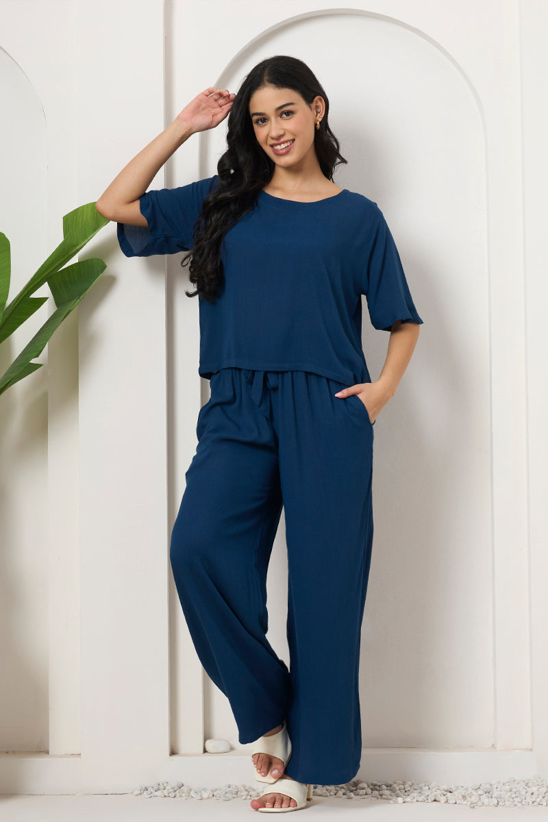 Woman standing in a teal crop top and wide leg pants