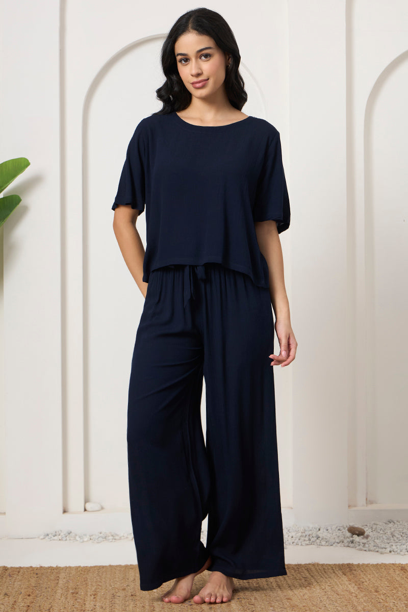 Woman standing in a navy crop top and wide leg pants