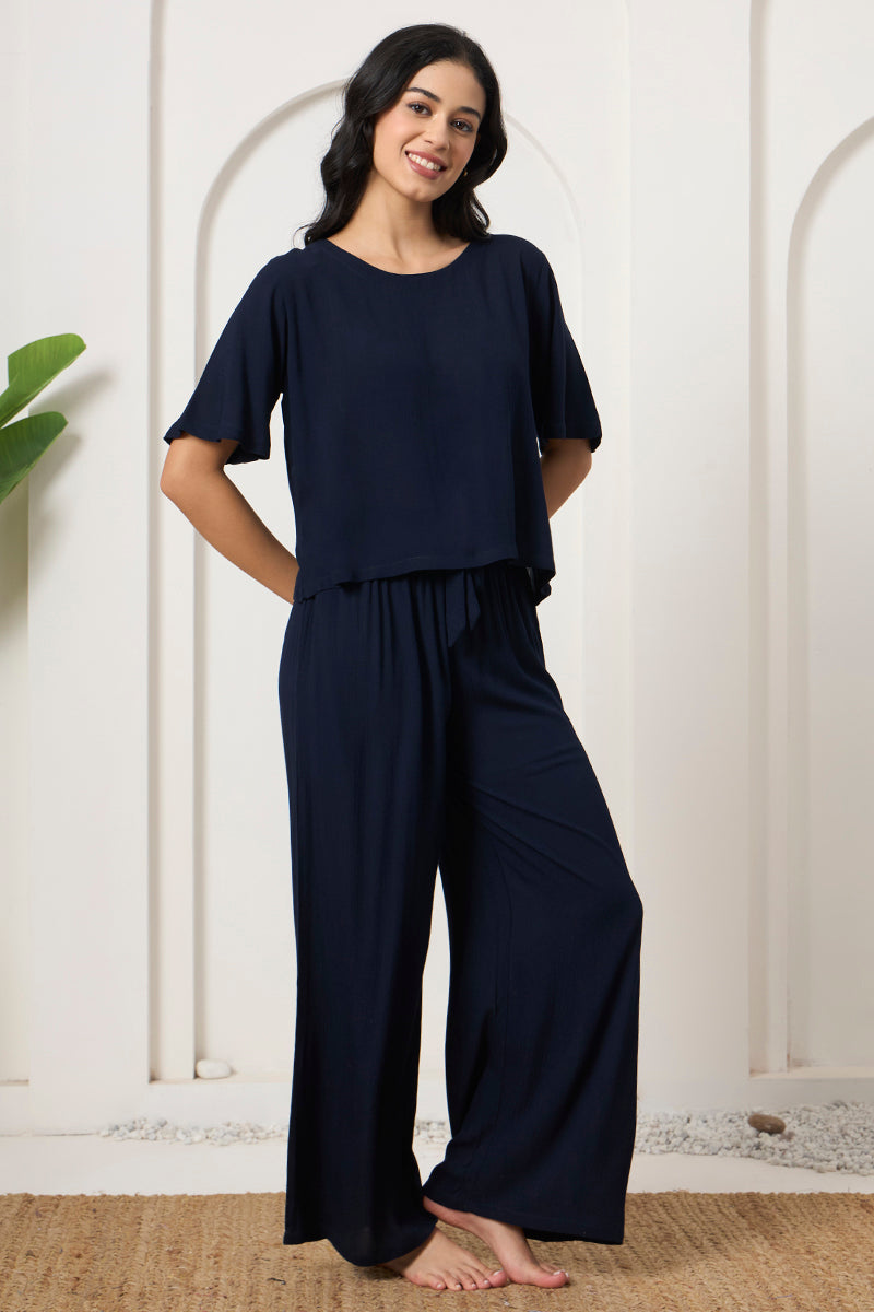 Woman smiling in a navy crop top and wide leg lounge pants