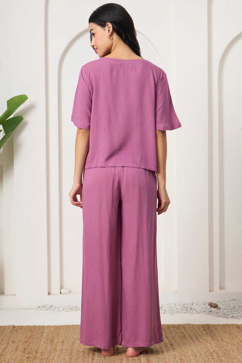 Back view of a woman wearing a mauve crop top and wide leg pants