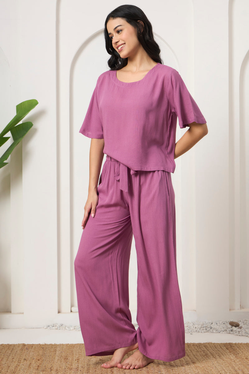 Woman posing in a mauve crop top and pants, looking to the side