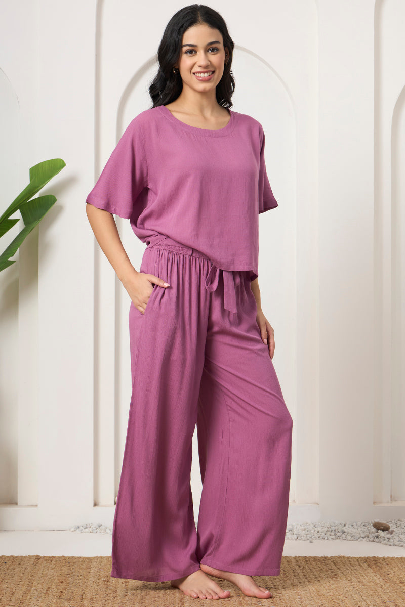 Woman standing in a mauve crop top and wide leg pants