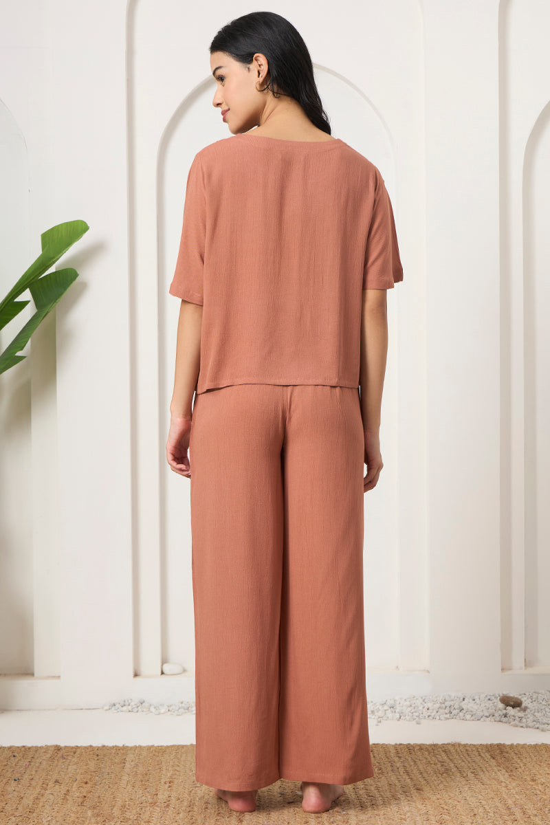 Back view of a woman wearing a rust crop top and wide leg pants
