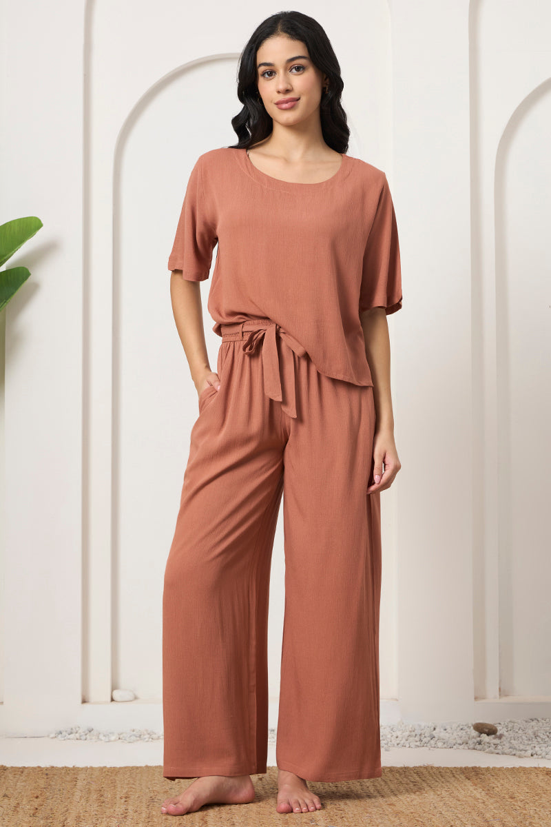 Woman standing in a rust crop top and wide leg tie waist pants