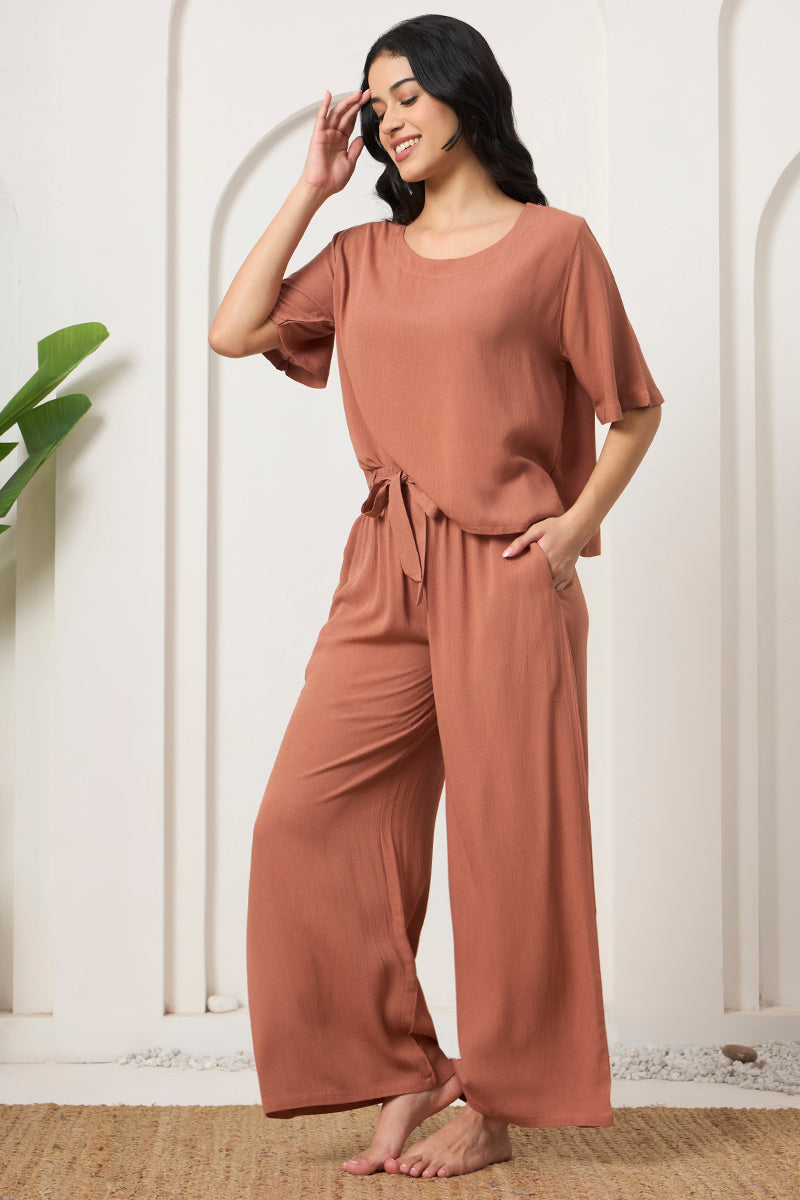 Woman smiling in a rust crop top and wide leg pants