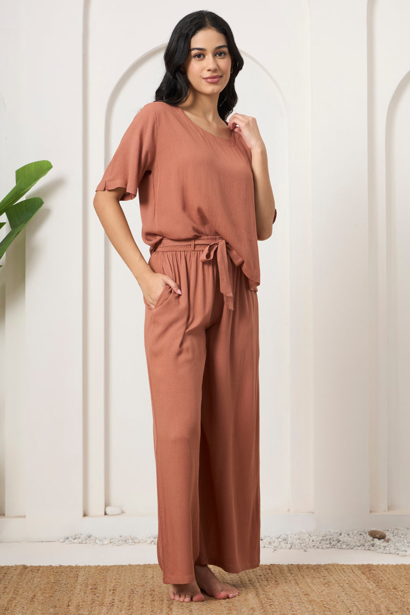 Woman posing in a rust crop top with tie waist wide leg pants