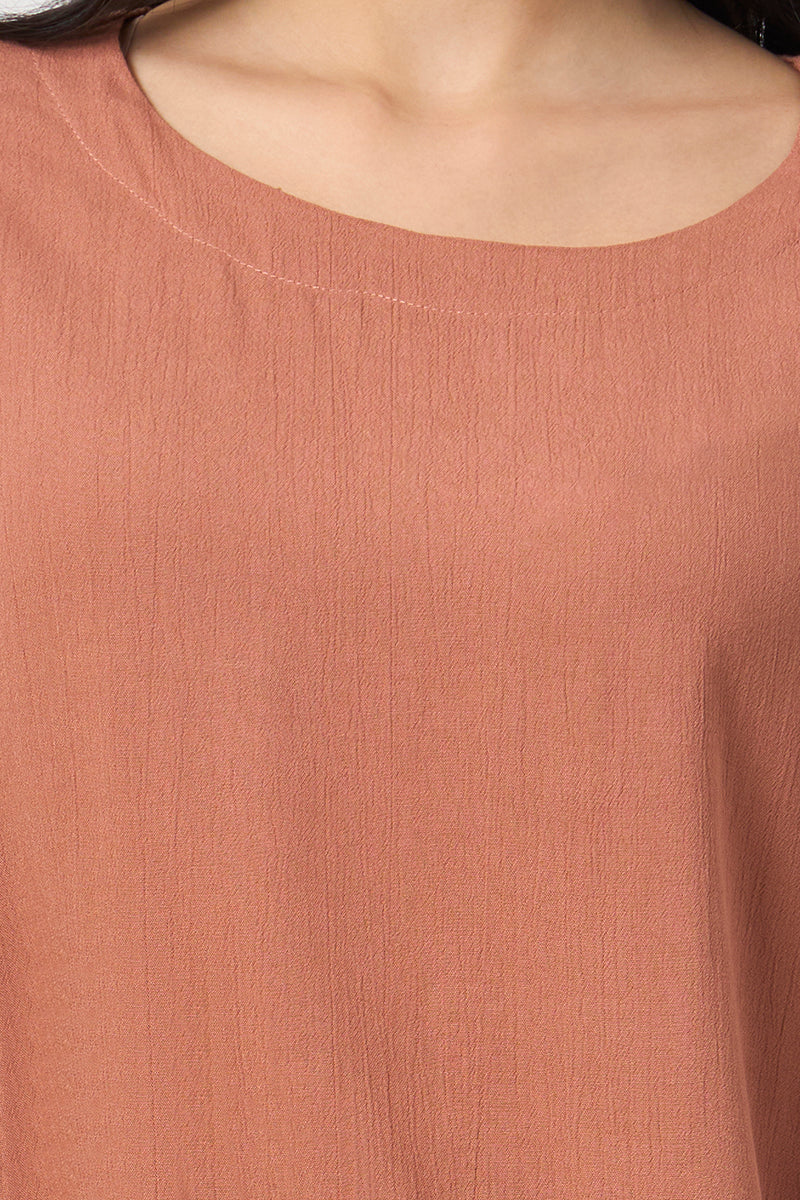 Close up of the round neckline and fabric texture on the rust top