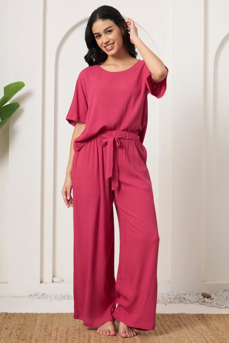 Woman smiling in a pink crop top and wide leg tie waist pants