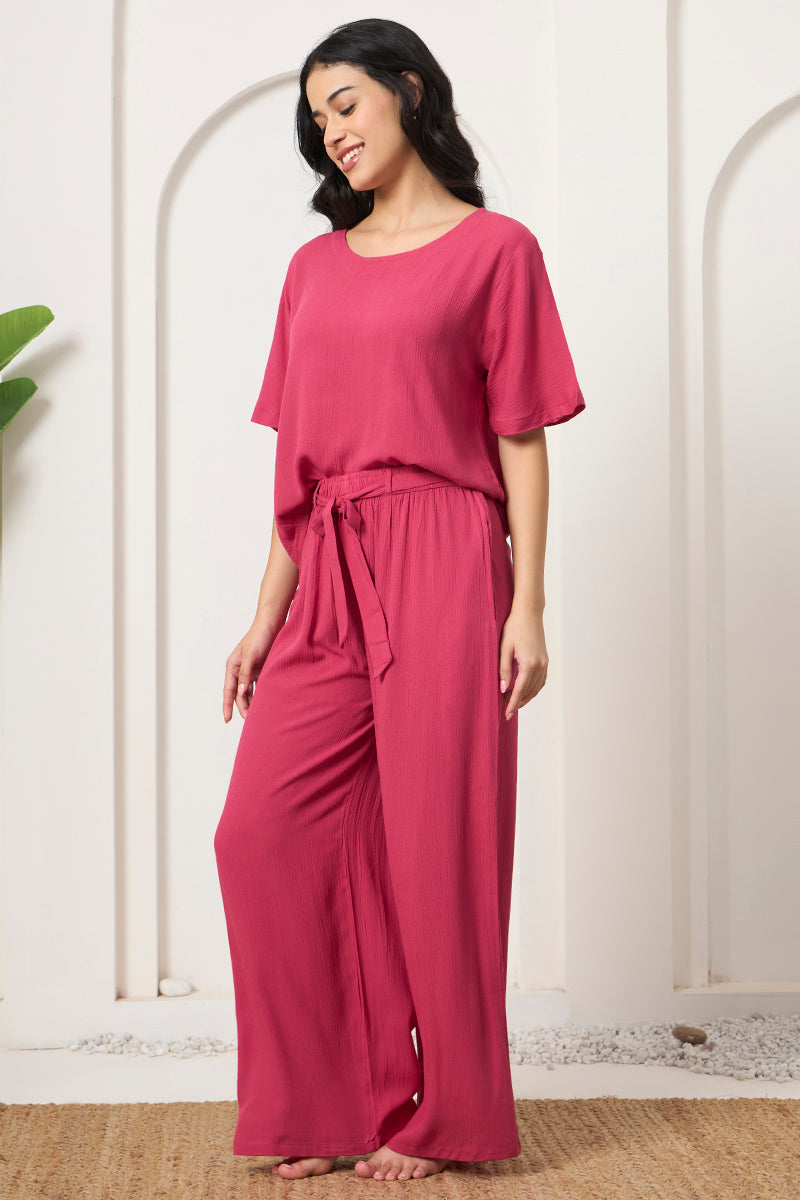 Woman standing in a pink crop top and wide leg pants
