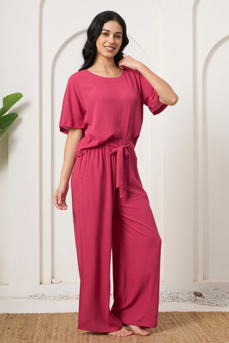 Woman posing in a pink crop top with tie waist wide leg pants