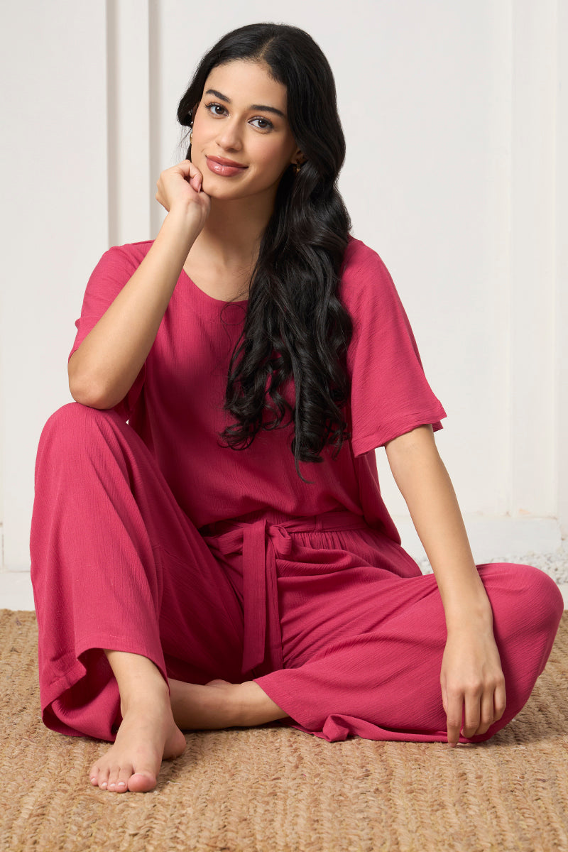 Woman sitting on a jute rug in a pink crop top and pants
