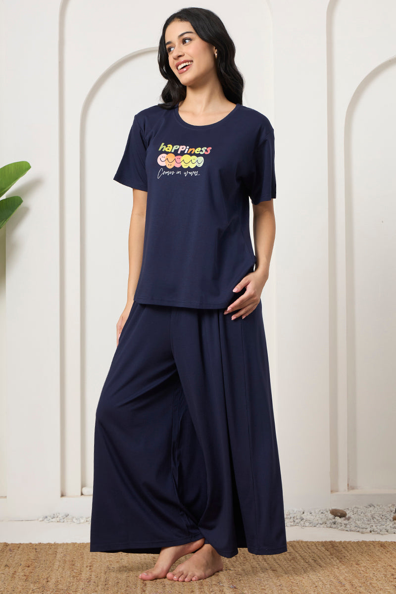 Woman smiling in a navy graphic print t-shirt and wide leg pants set