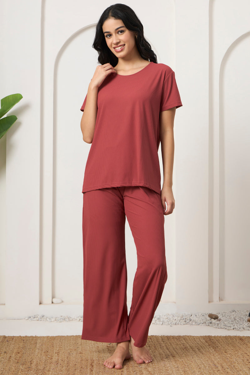 Smiling woman in a rust ribbed t-shirt and pyjama pants