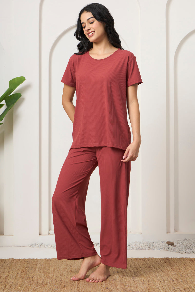 Woman in a rust ribbed loungewear set against an arched wall