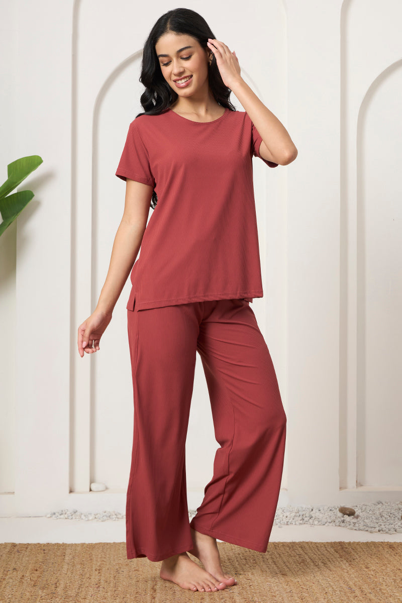 Woman smiling in a rust ribbed pyjama set on a jute rug