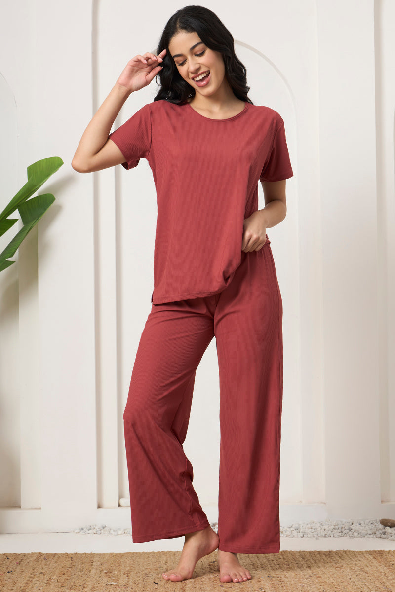 Woman in a rust ribbed lounge set with hand near waistband