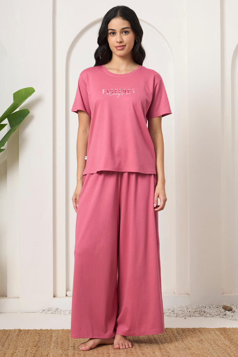 Woman standing in a pink graphic print t-shirt and wide leg pants set